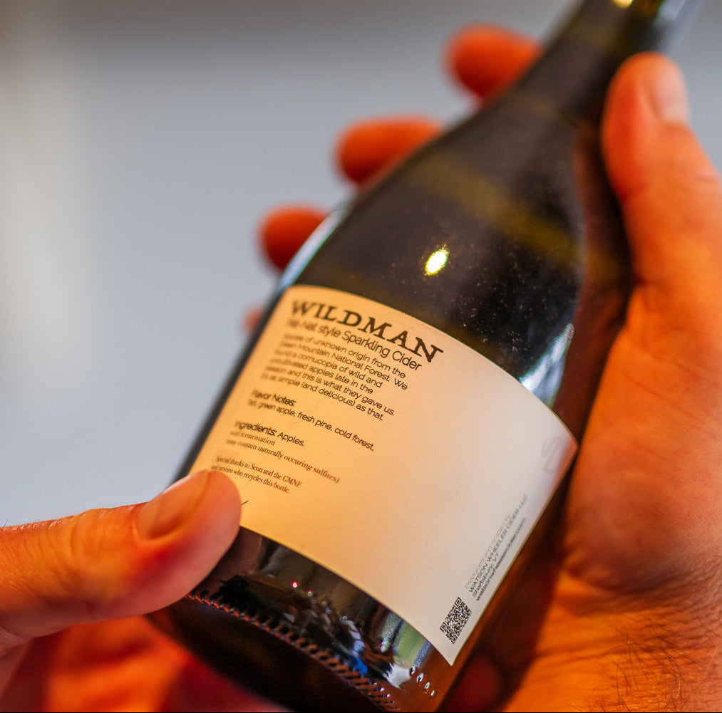 Hand holding a bottle of Wildman cider with a blurred background