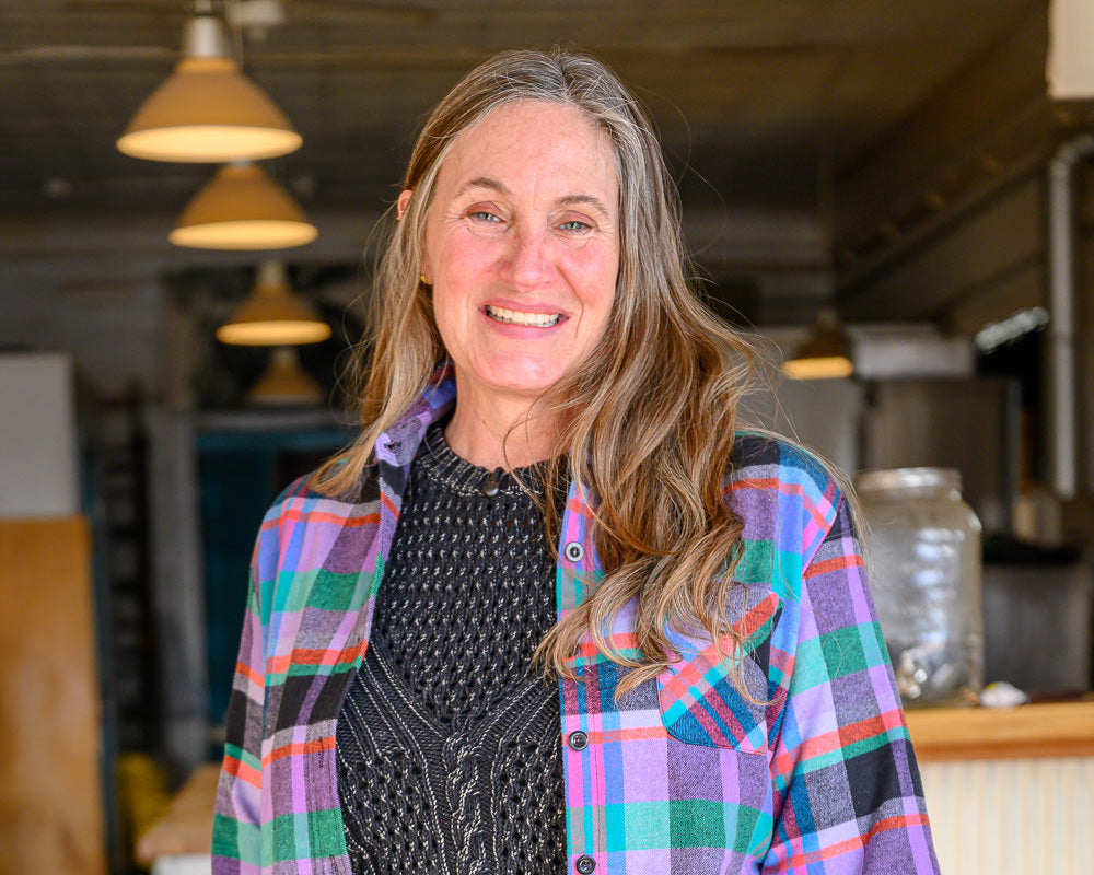 Jess wearing a colorful plaid shirt in an indoor setting