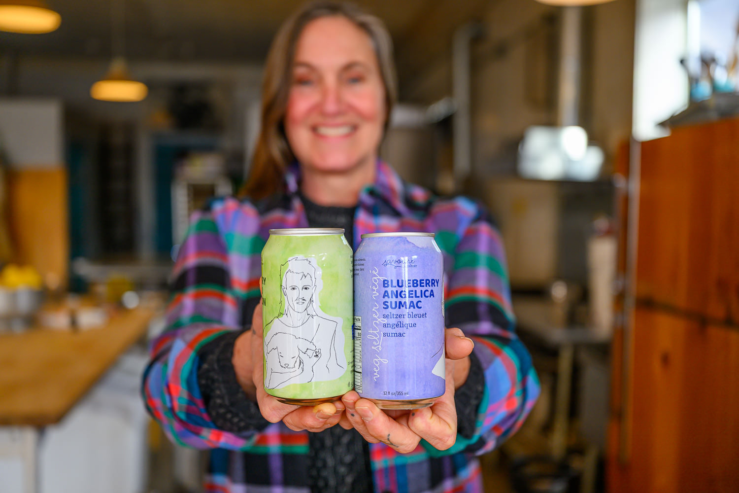 Jess holding two cans of Savoure in a kitchen setting